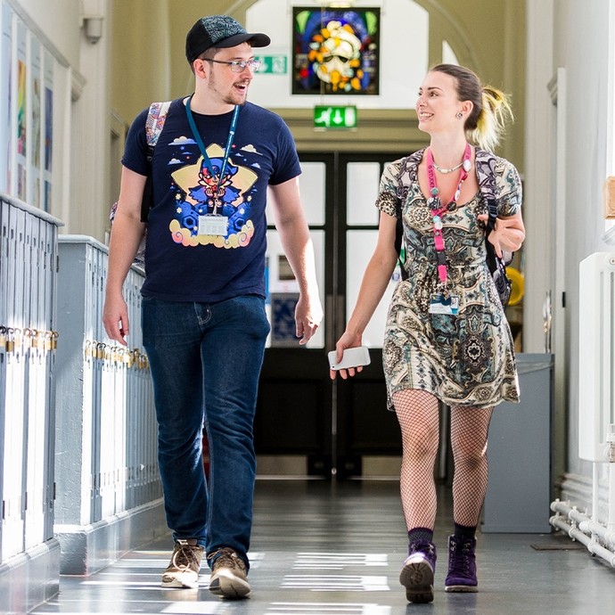 Two students walking down a corridor filled with lockers